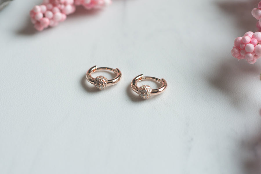 a pair of rose gold huggie hoop earrings