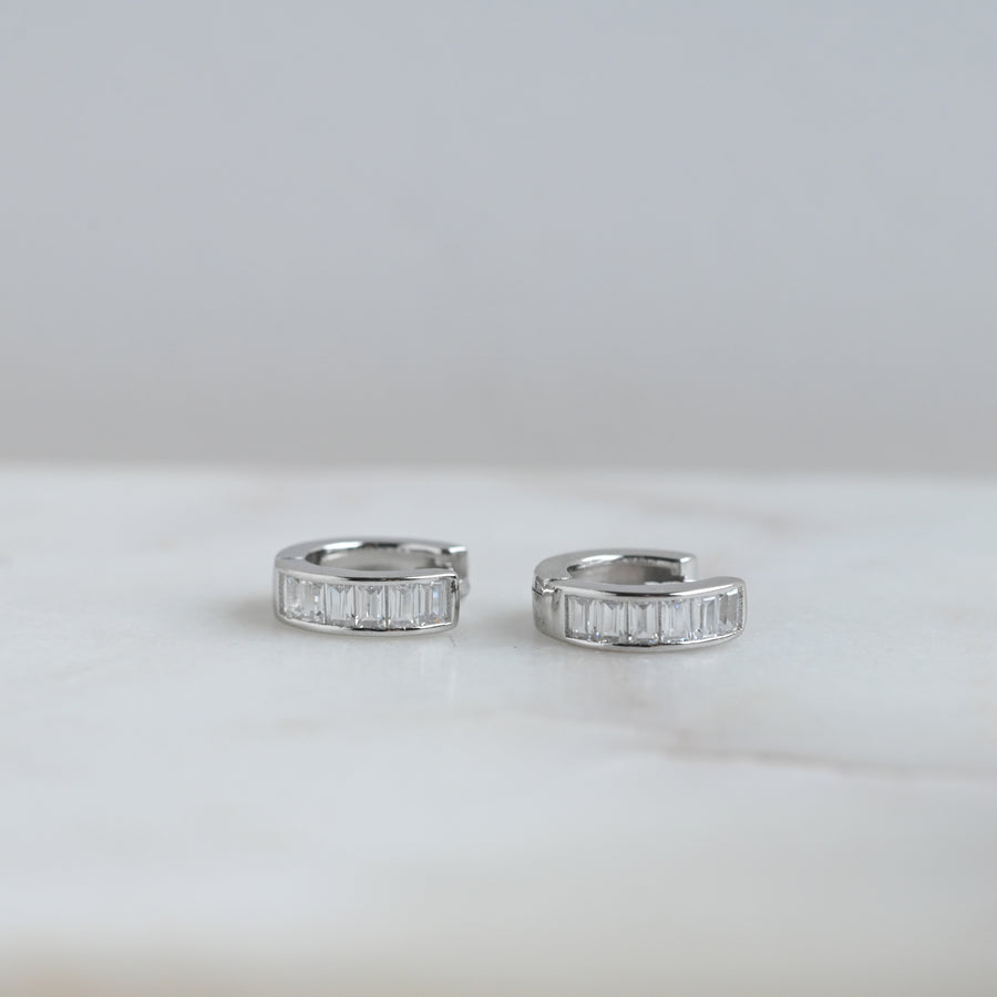a pair of silver small hoop earring with baguette stones