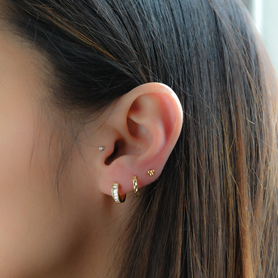 stacked earrings featuring baguette huggie earrings, plain gold hoops, and three ball studs 