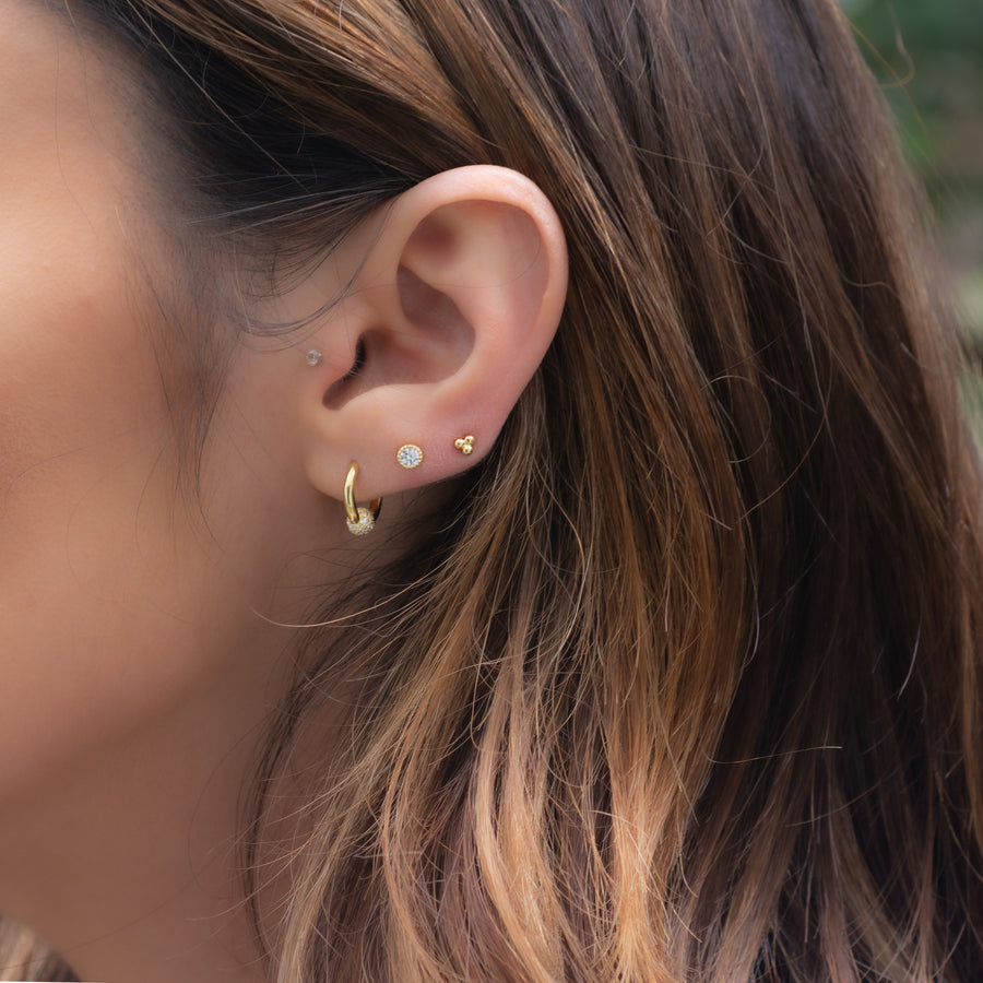 stacked gold earrings, of cz ball huggie hoops, diamond stud earrings, and tiny three ball studs