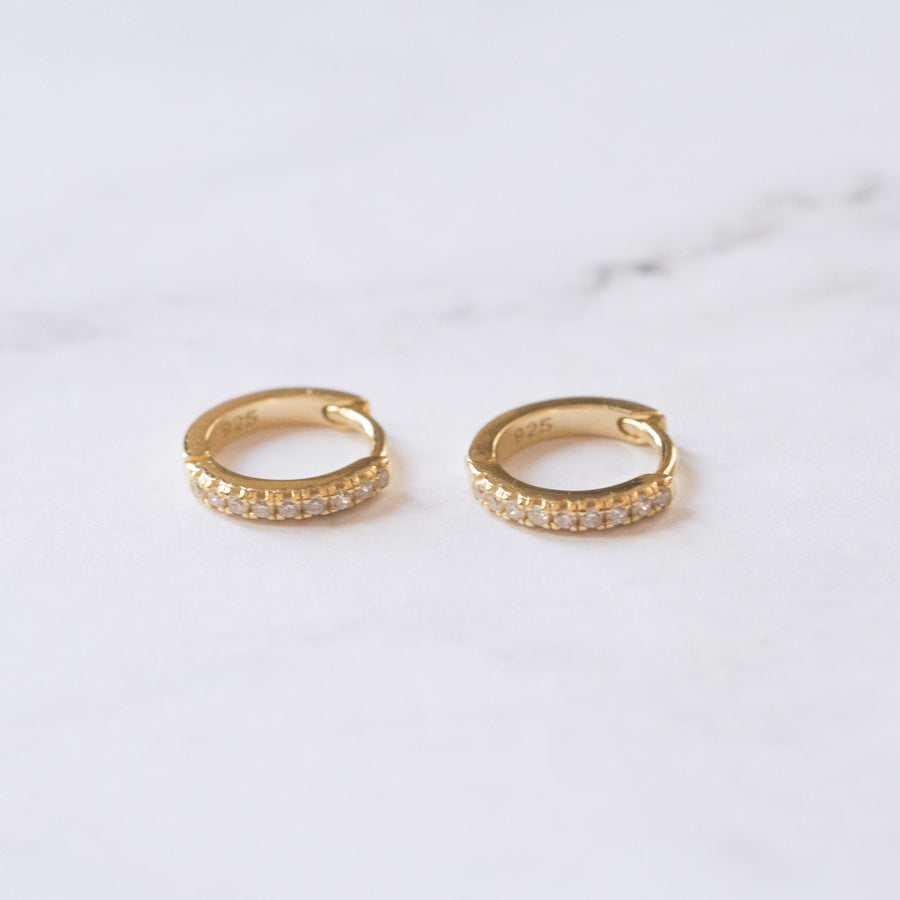 a pair of gold, small hoop earrings, with pave cubic zirconia stones