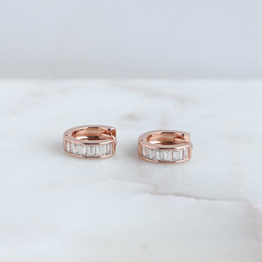 a pair of rose gold baguette studded small hoop earrings